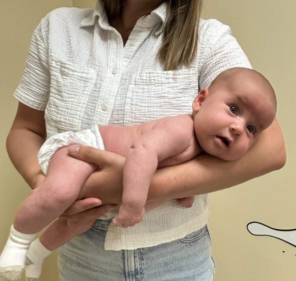 Physiotherapist holds baby on tummy